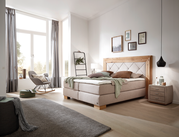 Boxspringbett Castell Boxspringbett in beigem Stoff, Kopfhaupt mit Massivholzumrandung, Knopfheftung und Sichtholzelementen in Wildeiche