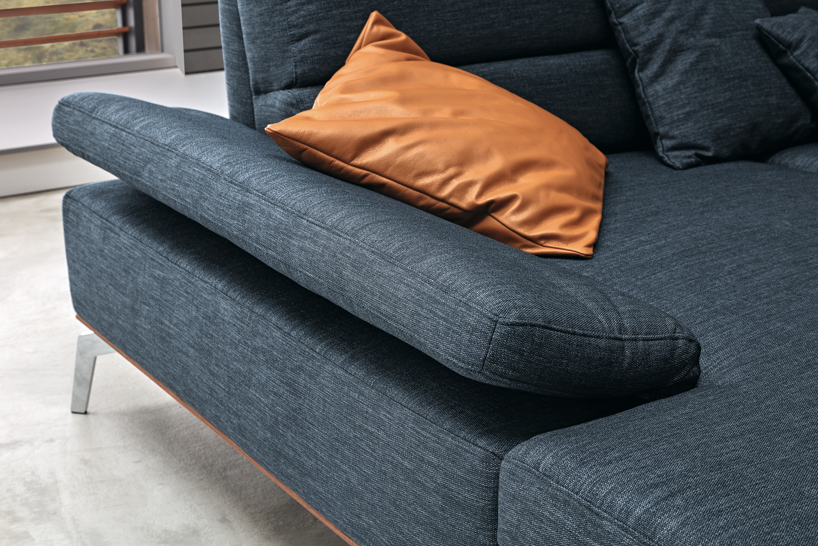 Armteilverstellung der Wohnlandschaft Tirano in blauem Stoff mit Holzsockel und Metallfüßen.