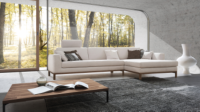 Ecksofa Tabora in hellem Stoff mit Holzsockel und Holzfüßen.