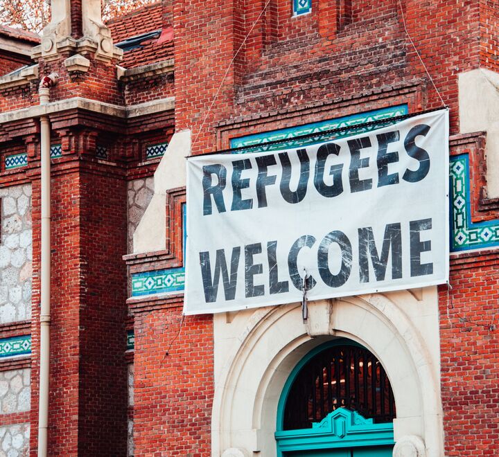 "Refugees Welcome" banner hanging on brick building