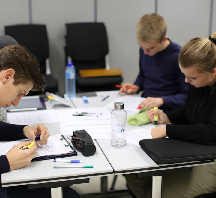 Tre studenter som sitter å studerer.