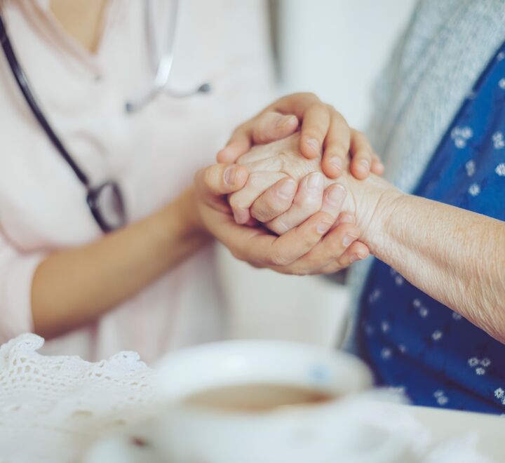 Lege og pasient holder hender