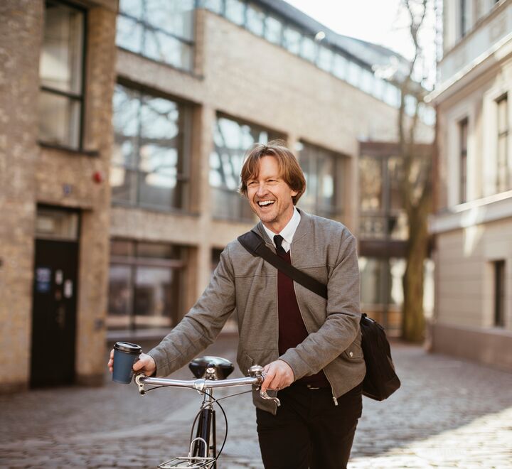 A happy man walking with his Caroline bicycle