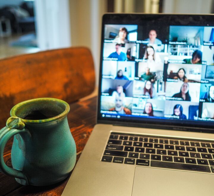 A cup of tea next to a computer with an online meeting