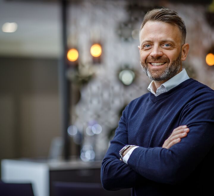 Smilende mann med hendene i kryss