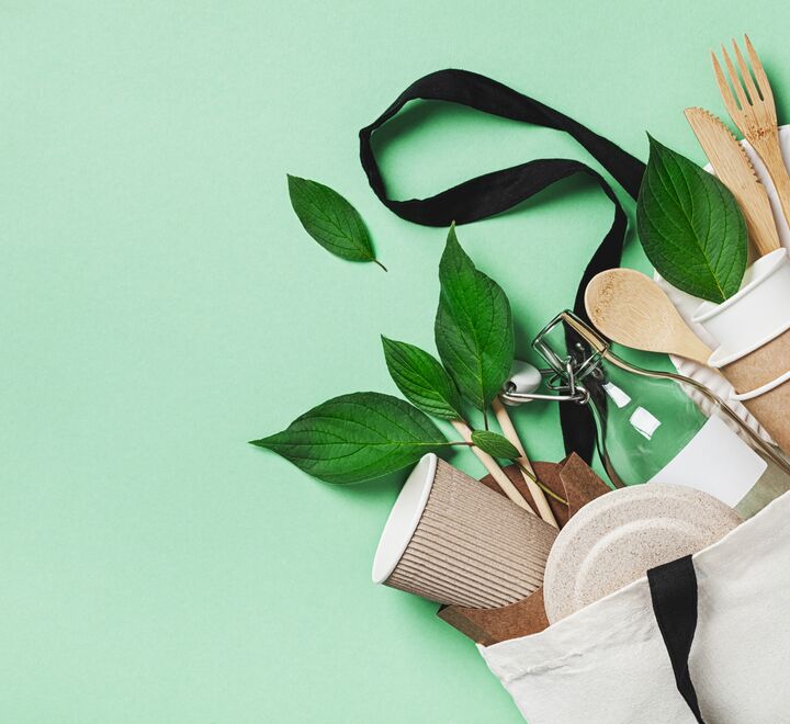 Plastic free set with eco cotton bag, glass jar, green leaves and recycled tableware top view