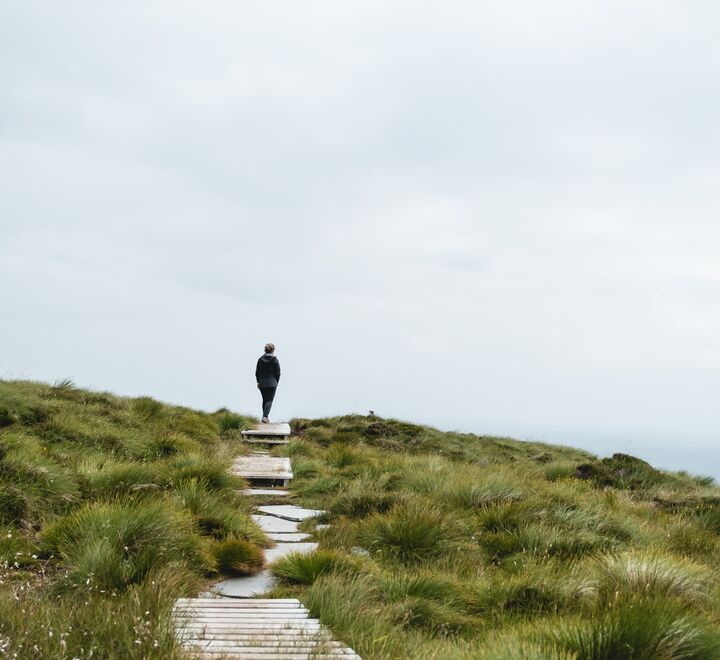 Person går bortover en sti i et grønt landskap.