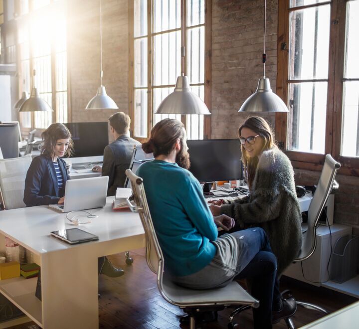 Ansatte i kontorlandskap som snakker sammen