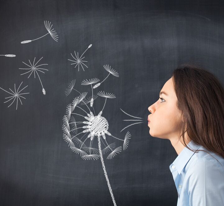 Woman blowing seeds of a dandelion