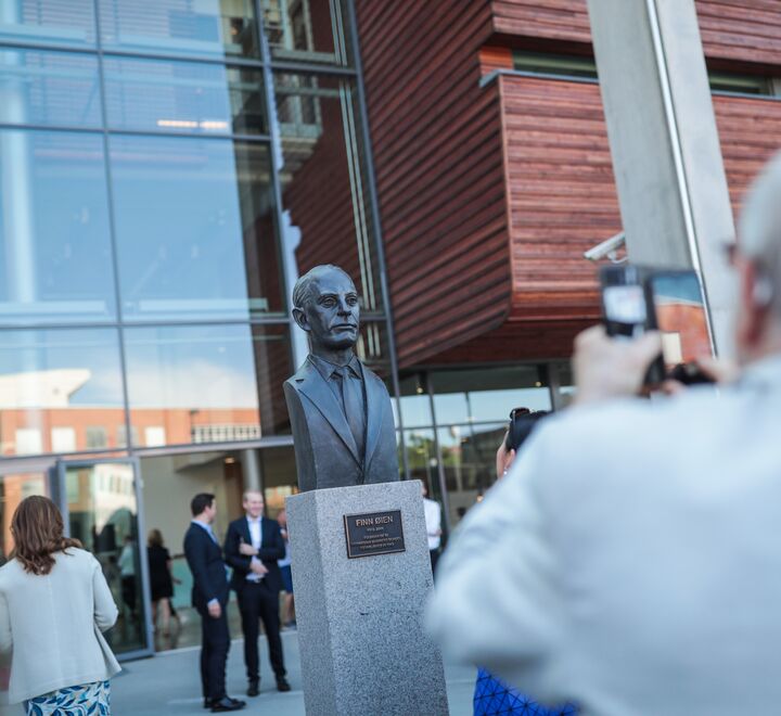 Outside of campus Oslo, with a statue of Finn Øien in front