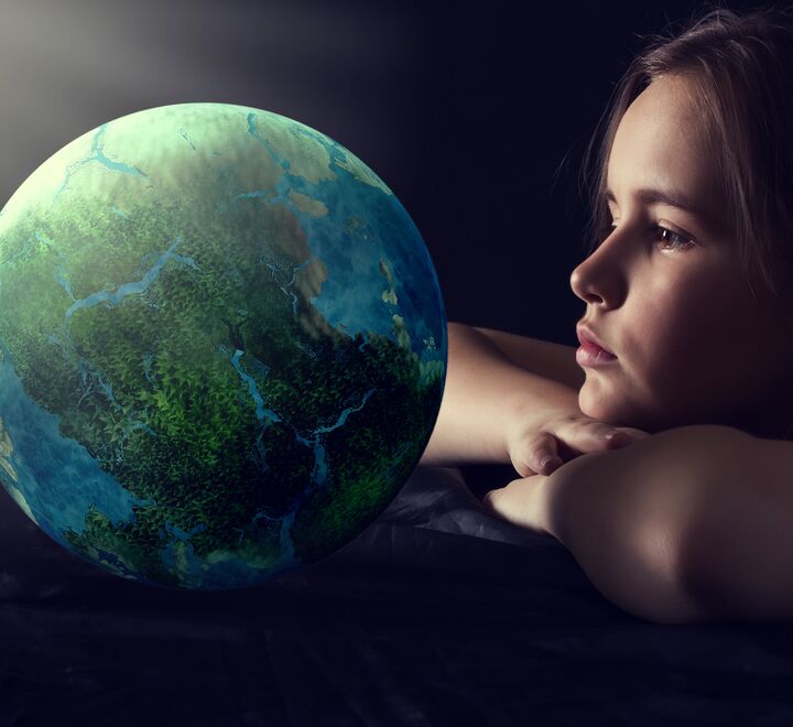 Liten jente som ser på en jordklode