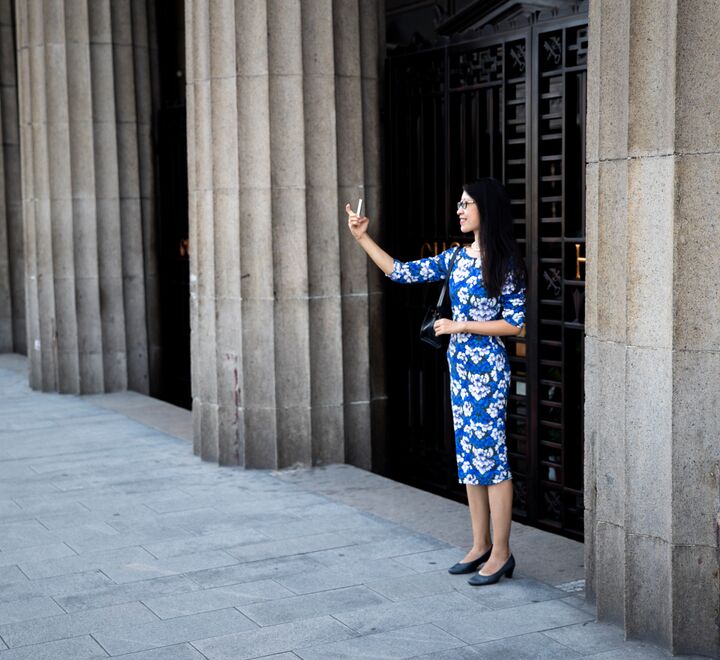 Kinesisk jente med mobil foran en bygning i Shanghai