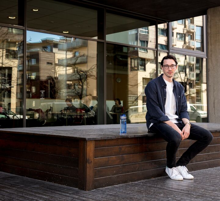 Bilde av en mann med briller foran campus