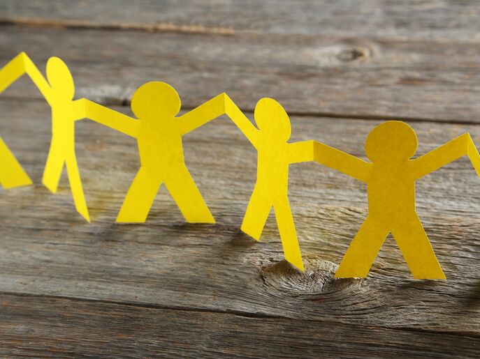 An image of a string of yellow paper people, holding each others hands.
