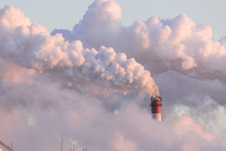 industrial chimneys with heavy smoke causing air pollution as ecological problem on pink sunset sky background	