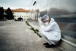 Depressed crying doctor with mask having mental breakdown.Fear,anxiety,panic attack due to coronavirus outbreak.Psychological effects of COVID-19.PTSD.Mental health,coping with death