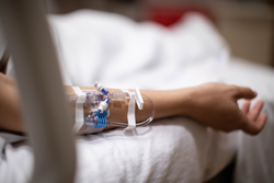 A hospitalized patient lying in in bed in critical condition, connected to an iv drip tube. Sick people in the hospital.