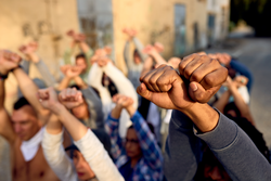 Close-up of large group of protesters with clenched fists above their heads on public demonstrations. 