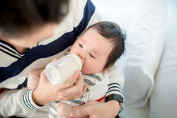 Dad feeding her baby daughter infant from bottle Adorable baby with a milk bottle. Baby milk eating bottle 