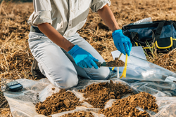 Soil Test. Agronomist putting soil with garden shovel in soil sample bag outdoor. Environmental research
