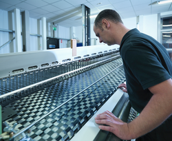 Worker operating carbon fibre loom in carbon fibre factory