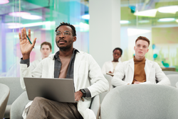 前视图被非洲裔美国人的画像g lab coat and raising hand asking question while sitting in audience and listening to lecture on medicine