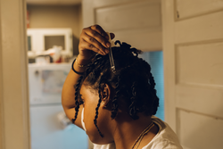 woman in her 20s taking a self care day by doing her hair, putting them in twist and oiling her scalp
