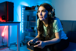 Young woman focusing on winning a video game with a remote controller. Female gamer enjoying a video game in a console during a leisure day in her bedroom