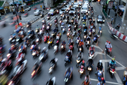 Blurred image of motorcycle taxis and 
motorcyclist  weave through Bangkok's during intense rush-hour traffic.They keep things moving. When the light changed to green,
they were the first people away.