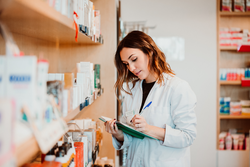 Young female pharmacist working in her large pharmacy. Placing medications, taking inventory. Lifestyle