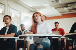Student paying attention to lecture in classroom. Woman studying at the college classroom.