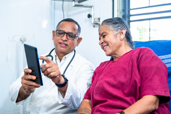 Doctor explaining from tab to senior pateint about health condition after surgery - concept of technology, health care and relaxation.