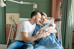 A Mother and father with her newborn baby at the hospital a day after a natural birth labor