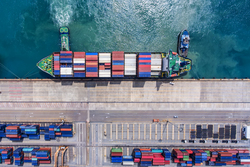 Container ship in export and import business and logistics. Shipping cargo to harbor by crane. Water transport International. Aerial view