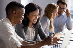 Happy senior old korean businesswoman discussing online project on laptop with african american male colleague, working together in pairs at shared workplace, analyzing electronic documents.