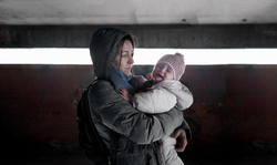 Caring mother holding her crying baby in the air raid shelter