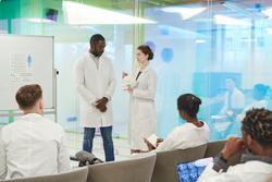 Portrait of young woman standing by whiteboard while giving presentation during medical seminar in college, copy space