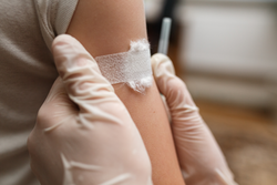 Child with a medical tape on his shoulder after a vaccination injection. Prevention of diseases in children through vaccination. Health care and medicine concept. Focus on shoulder.