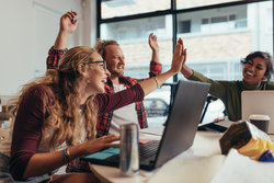 Group of young business team giving high five and celebrating success at office. Cheerful startup business team rejoicing success at office.
