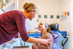 Disabled child in a wheelchair being cared for by a special needs nurse / Working with disability