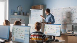 Elementary School Class: Teacher Uses Interactive Digital Whiteboard, Explains Lesson to Diverse Group of Smart Children. Kids getting Modern Education, Learn Computer Science, Software Programming