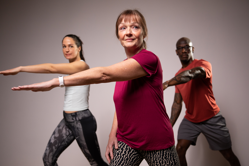Three people stretch their arms to the side